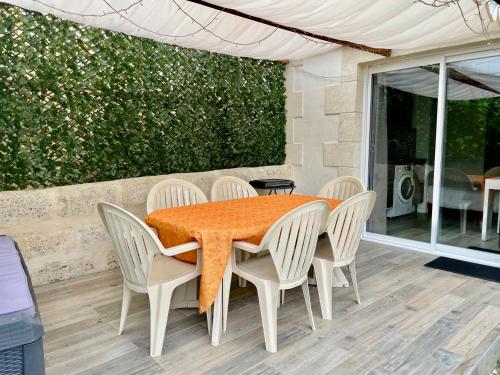 une table avec des chaises blanches et un chiffon de table orange dans l'établissement Studio au calme climatisé avec terrasse, à Paillet