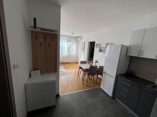 a kitchen with a white refrigerator and a table at Cozy Apartment Anna in Subotica