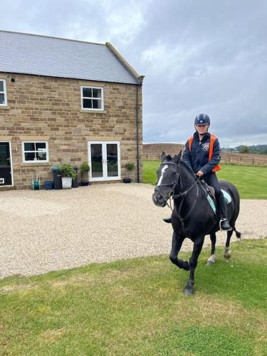 a person riding a horse in front of a building at Foxhall Farm in Thirsk