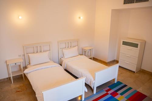 a bedroom with two beds and a dresser at Wateera Jebel Sifah in As Sīfah
