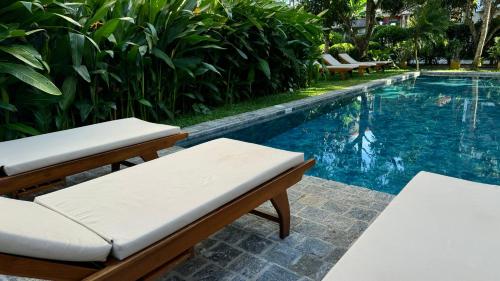 a swimming pool with two lounge chairs next to it at Peacock Villa in Mirissa