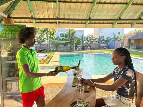 two people sitting at a table with a bottle of wine at Babylon Gardens Diani in Ukunda