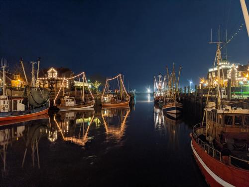 a group of boats docked in a harbor at night at Drei-Insel-Blick Neßmersiel in Neßmersiel