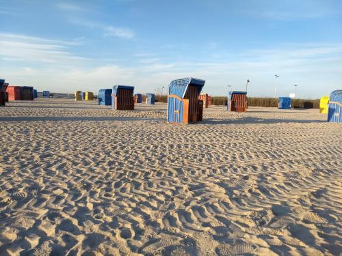 a row of beach huts on a sandy beach at Drei-Insel-Blick Neßmersiel in Neßmersiel