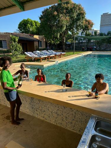 a group of people sitting around a table by a swimming pool at Babylon Gardens Diani in Ukunda