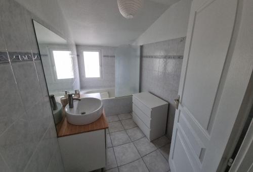 een witte badkamer met een wastafel en een bad bij Maison in Sainte-Marie-la-Mer