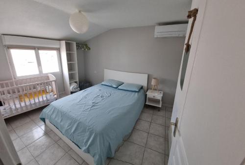 een slaapkamer met een bed met blauwe lakens en een wieg bij Maison in Sainte-Marie-la-Mer