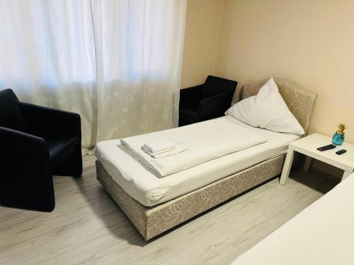 a bed in a room with two chairs and a table at Carla Maria S Hause in Gammertingen