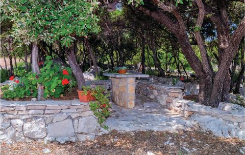 a stone wall with a table and some flowers at Holiday Home Zastrazisce With Sea View 04 in Selca kod Bogomolja
