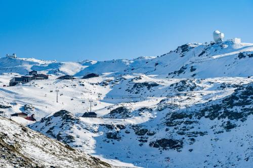 a snow covered mountain with a ski lodge on it at Apartamentos Boabdil in Sierra Nevada