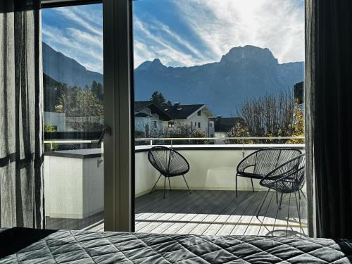 a bedroom with a view of a balcony with two chairs at Appartment Haus Einbergblick in Abtenau