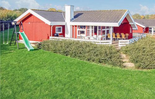 a red house with a playground and a swing at Holiday Home Hvedemarken Sjølund Iii in Hejls