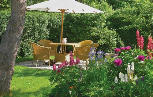 a table with an umbrella in a garden with flowers at Two-Bedroom Holiday Home In Dronningmolle in Dronningmølle