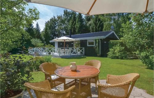 a table with chairs and a vase on top at Two-Bedroom Holiday Home In Dronningmolle in Dronningmølle