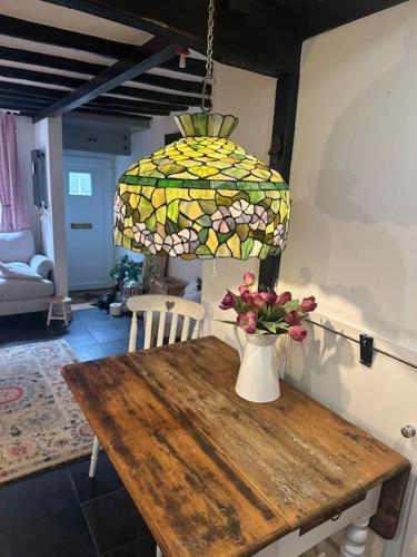 a table with a lamp and a vase with flowers on it at Love Lane Cottage Dolgellau in Dolgellau