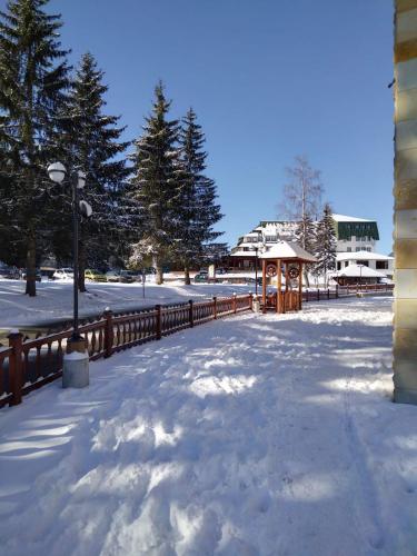 a snow covered park with a fence and a gazebo at Apartman Petar in Nova Varoš