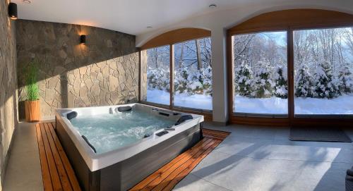 a large bathroom with a hot tub in front of windows at Willa Góralka in Szczyrk
