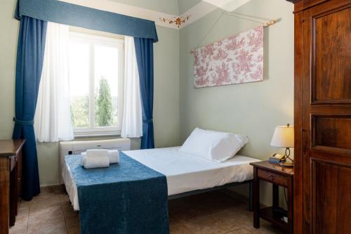 a bedroom with a bed with blue curtains and a window at Borgo San Martino - Residence Hotel & SPA in Riparbella