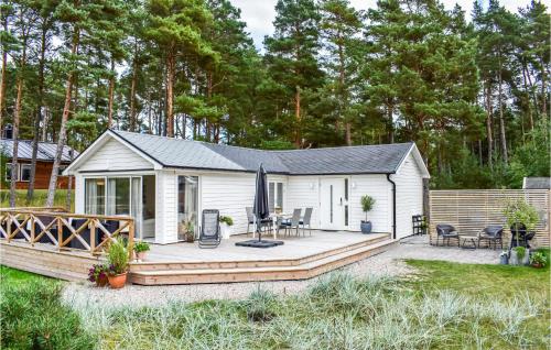 a small white cabin with a deck in a yard at Cozy Home In Yngsjö With Kitchen in Yngsjö
