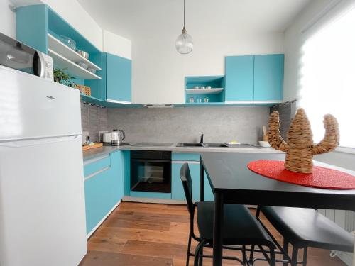 une cuisine avec des placards bleus et une table avec des chaises dans l'établissement L'Écureuil, à Calais