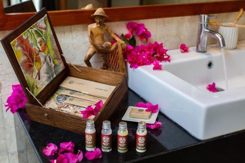 a bathroom counter with a sink and a bath tub and flowers at Delight ART Villas in Seminyak
