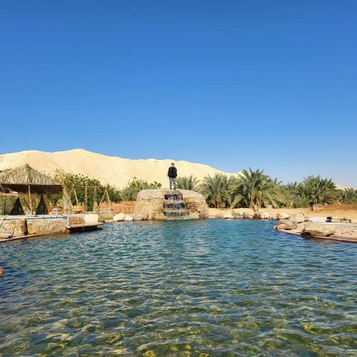 a man standing on a rock in a pool of water at Qasr El Bagawat Hotel in ‘Ezbet Halfa