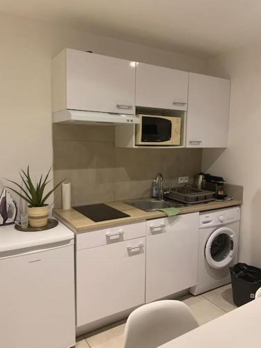- une cuisine avec des placards blancs, un four micro-ondes et un lave-linge dans l'établissement Superbe studio proche palais et plages à pieds, à Cannes