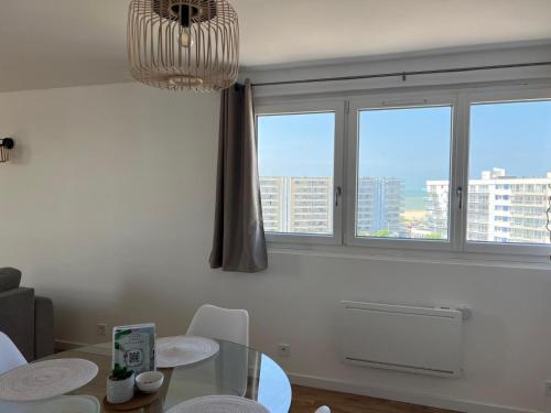 une salle à manger avec une table et deux fenêtres dans l'établissement L'Escale Calaisienne, à Calais