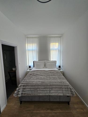 a white bedroom with a large bed with white pillows at Regal Retreats in Zagreb