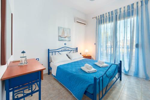 a bedroom with a blue bed with towels on it at Stegna House Sea View in Archangelos