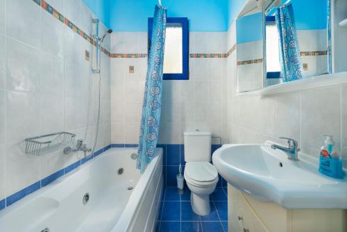 a bathroom with a toilet and a sink and a bath tub at Stegna House Sea View in Archangelos