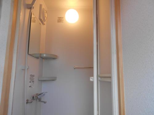 a bathroom with a shower with a light on the wall at Guest House Honami-Kaido in Yamanouchi