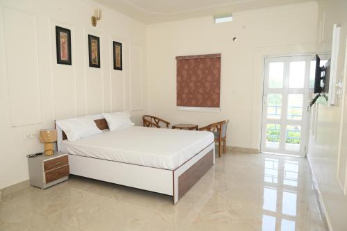 a white bedroom with a bed and a table at shangrila stay in Bodh Gaya