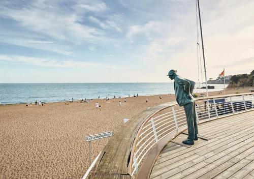 une statue d'un homme sur une promenade à côté d'une plage dans l'établissement Les Verrières・Studio à 400m de la mer・Netflix, à Saint-Nazaire