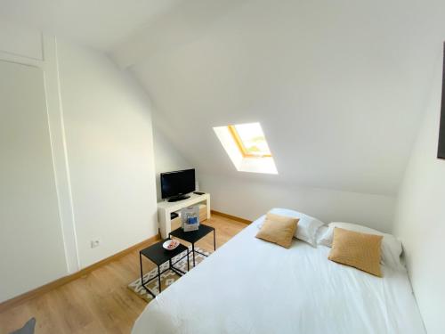 une chambre blanche avec un lit et une télévision dans l'établissement Les Dunes 2, à Sangatte