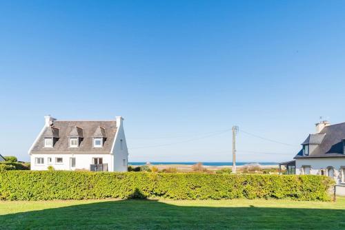 une maison avec une haie et l'océan en arrière-plan dans l'établissement Maison spacieuse vue sur mer a Pleubian, à Pleubian