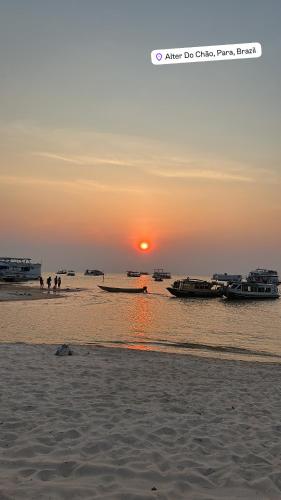 a sunset on a beach with boats in the water at Flat Alter do chão - Ilha bela Residence in Alter do Chao