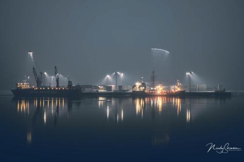 a view of a factory on the water at night at ATCON Business Apartments in Nuuk