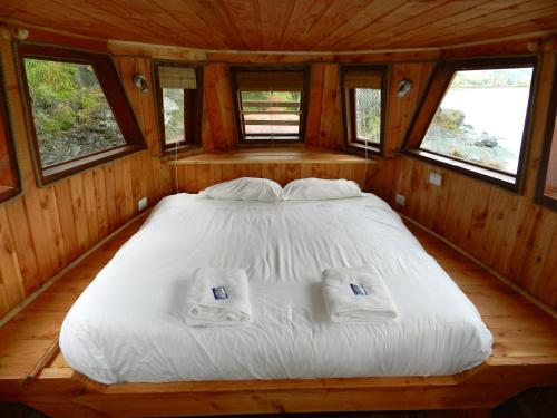 a large bed in a wooden room with windows at Terra Luna Lodge in Puerto Guadal