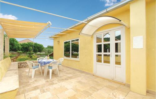 a patio with a table and chairs and a white door at Two-Bedroom Apartment In Racisce in Račišće