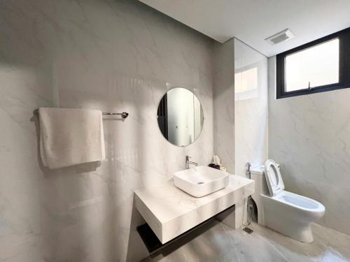 a white bathroom with a sink and a toilet at Lotus Wyndham Thanh Thủy in Phú Thọ