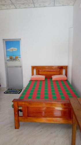 a bedroom with a wooden bed with a red and green stripes at Wasana Guest Yala in Kirinda