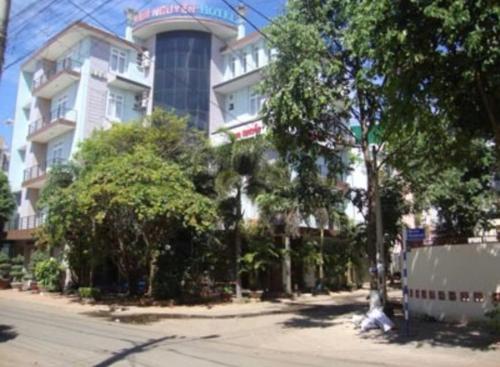 a large white building with trees in front of it at Khách Sạn Nam Nguyên in Buon Ma Thuot