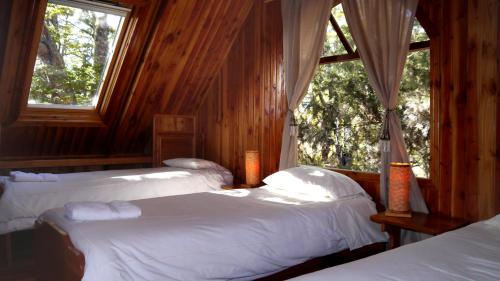 two beds in a room with two windows at Terra Luna Lodge in Puerto Guadal