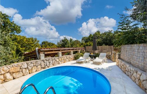 una piscina con due sedie e un muro di pietra di 3 Bedroom Awesome Home In Krk a Risika