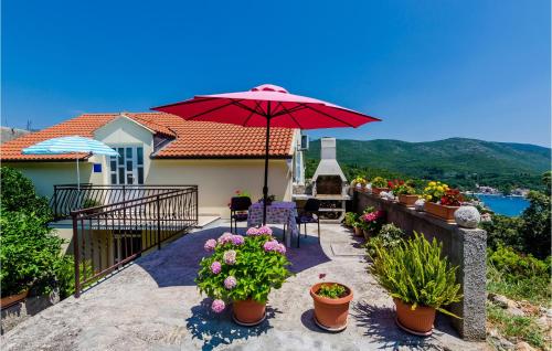 a balcony with a red umbrella and some flowers at Apartment Gruda With Sea View 02 in Molunat