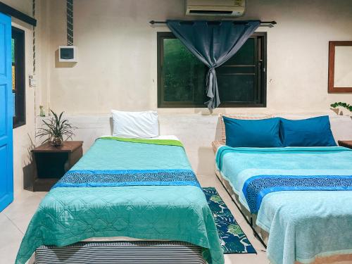 two beds sitting in a room with a window at Baan Suanthip Homestay - Aoluek Natural Retreat in Ao Luk