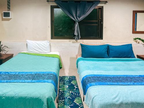 two beds sitting in a room with a window at Baan Suanthip Homestay - Aoluek Natural Retreat in Ao Luk