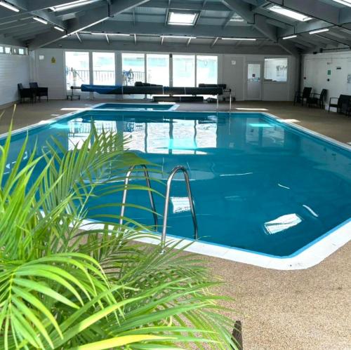 a large swimming pool in a large building at Sunset sea view chalet with hot tub in Torpoint