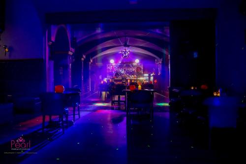 a dark room with purple lights and tables and chairs at Goa Country Club Near Park Hospital BY Pearl I Luxury resort in Gurgaon in Gurgaon
